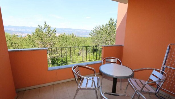 A balcony with a table and chairs, a view of trees and mountains, and orange walls. - Apartment Dudovic Darko nr 4 (Silo - island Krk)