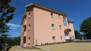 A multi-story building with a flat roof, a balcony on the second floor, and a paved courtyard. - Apartment Dudovic Darko nr 4 (Silo - island Krk)