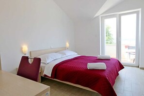 Quarto de hotel com uma cama, uma escrivaninha e uma cadeira. Há uma janela com vista para o exterior.