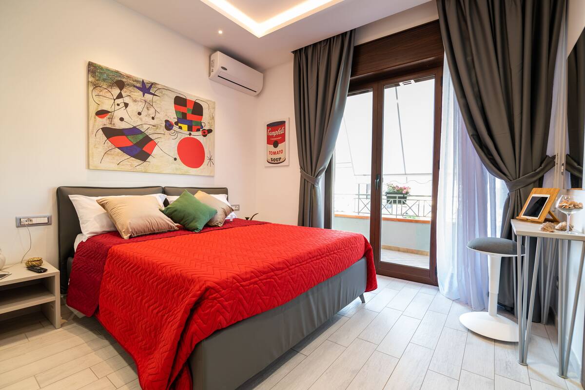 Un dormitorio moderno con una cama grande, una mesita de noche, una silla y vistas al balcón.