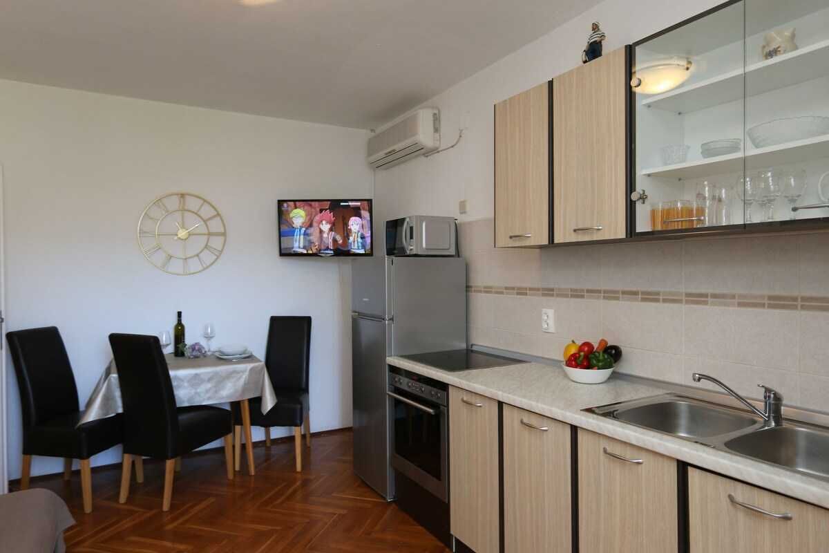 A compact kitchen with a dining area, a microwave, a refrigerator, and a sink.