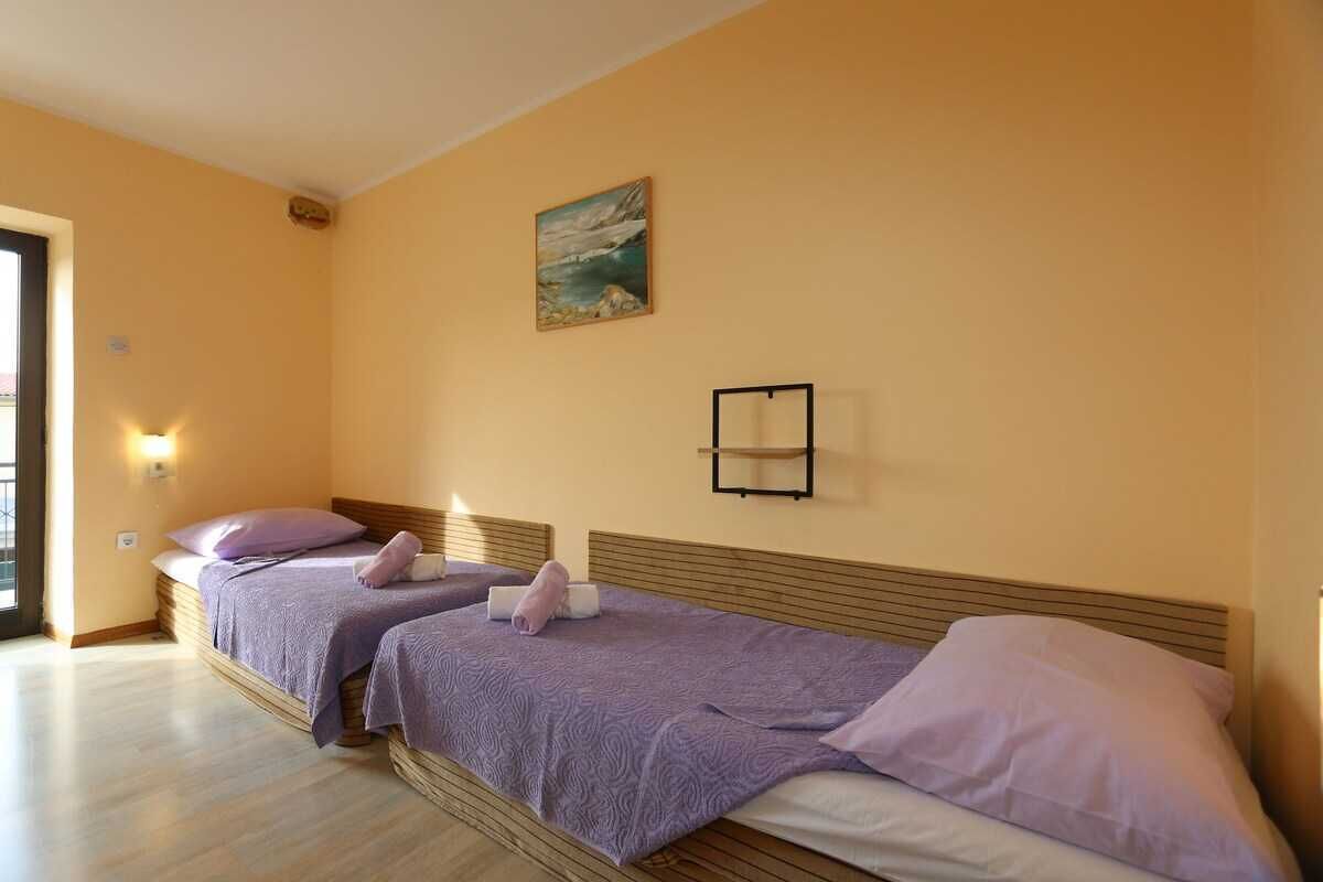Quarto com duas camas, um quadro na parede e uma prateleira pequena.