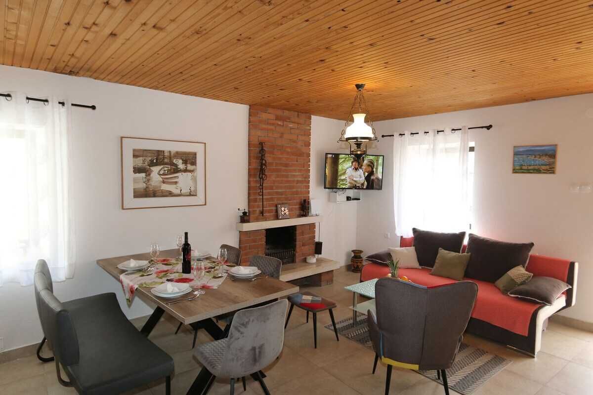 A dining area with a table set for four, a sofa, and a TV mounted on the wall.