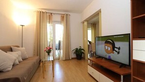 A living room with a sofa, TV, wooden cabinet, and a potted plant. - Apartment Brusic dole (Silo - island Krk)