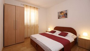 A bedroom with a bed, bedside tables, a wardrobe, and a painting on the wall. - Apartment Brusic dole (Silo - island Krk)