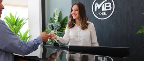 Un mostrador de recepción de hotel con un logotipo y una recepcionista.