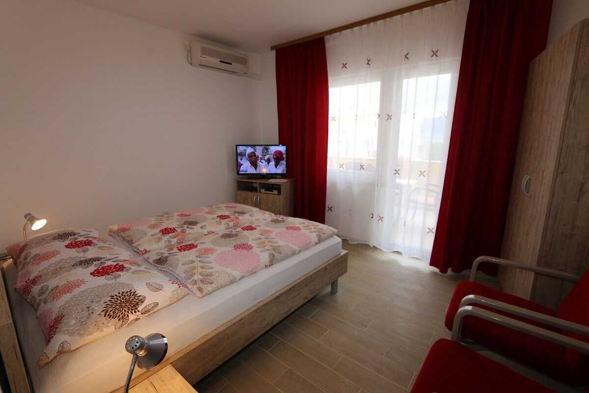 Ein Schlafzimmer mit Bett, Fernseher, Schreibtisch und Stuhl.