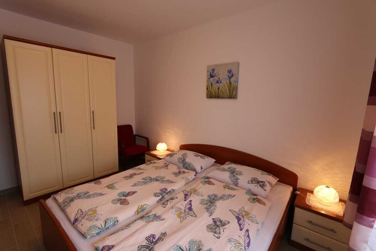 Un dormitorio con cama, mesitas de noche, un armario y un cuadro en la pared.