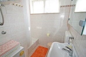 Een badkamer met een bad, toilet en douche.