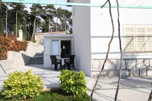 Een modern gebouw met een terras, buitenmeubels en een kleine tuin.