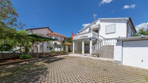 A courtyard with cobblestone paving, a white building with a balcony, and a stone wall.