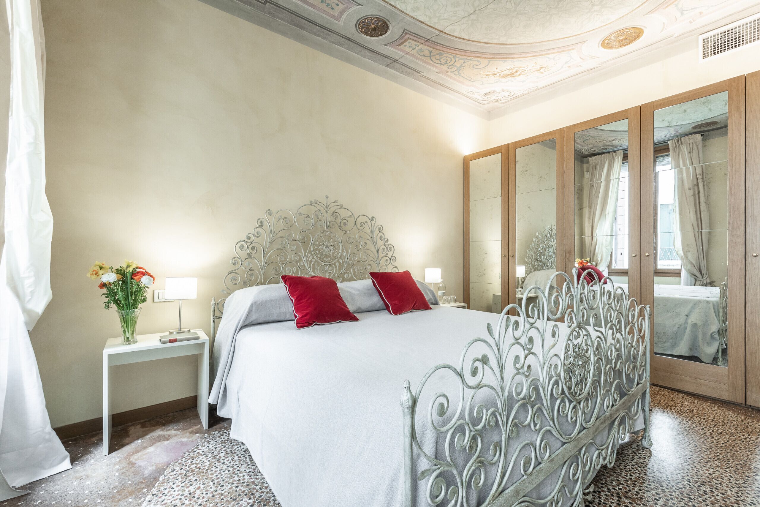 A neatly arranged bedroom with a bed, bedside tables, and a mirror.