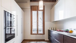 Une cuisine avec des meubles blancs, un plancher en bois et une fenêtre donnant sur l’extérieur.