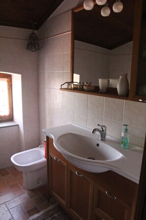 Ein Badezimmer mit einem weißen Waschbecken, Holzschränken, einem Spiegel und einem Fenster.
