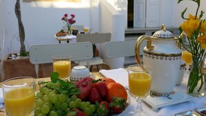 Une table de petit-déjeuner avec des fruits, un pichet de jus d’orange et une théière.