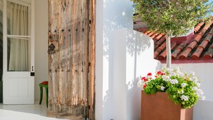 Une porte en bois rustique, un mur blanc, un sol carrelé et un jardinière remplie de fleurs.