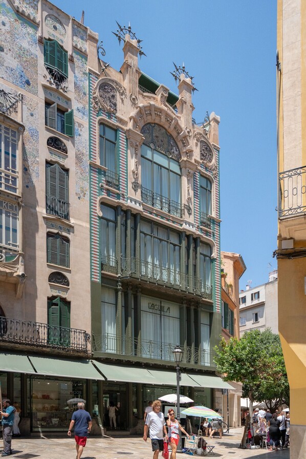 A historic building with ornate architectural details, large windows, and a green awning.