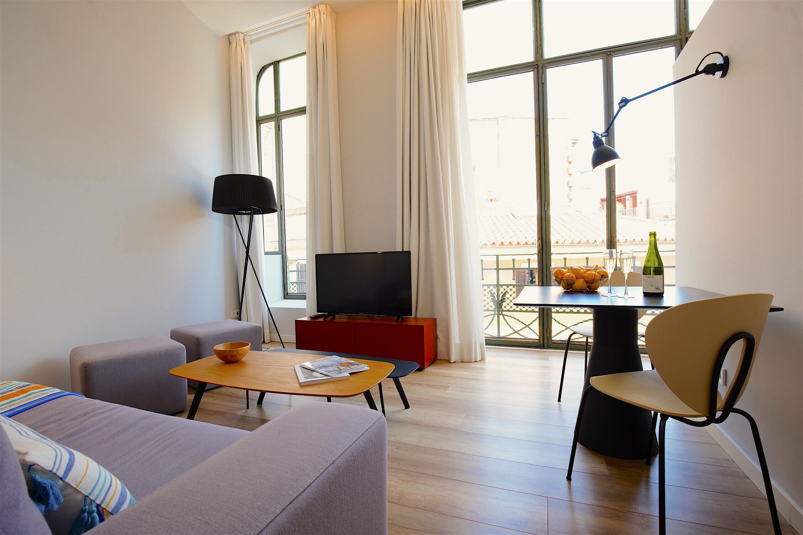 Een moderne woonkamer met een bank, een salontafel, een televisie en een eethoek met een tafel en stoelen.