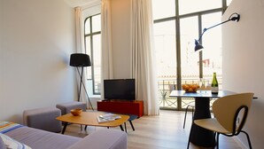 Una sala de estar moderna con un sofá, una mesa de centro, un televisor y un comedor con una mesa y sillas.