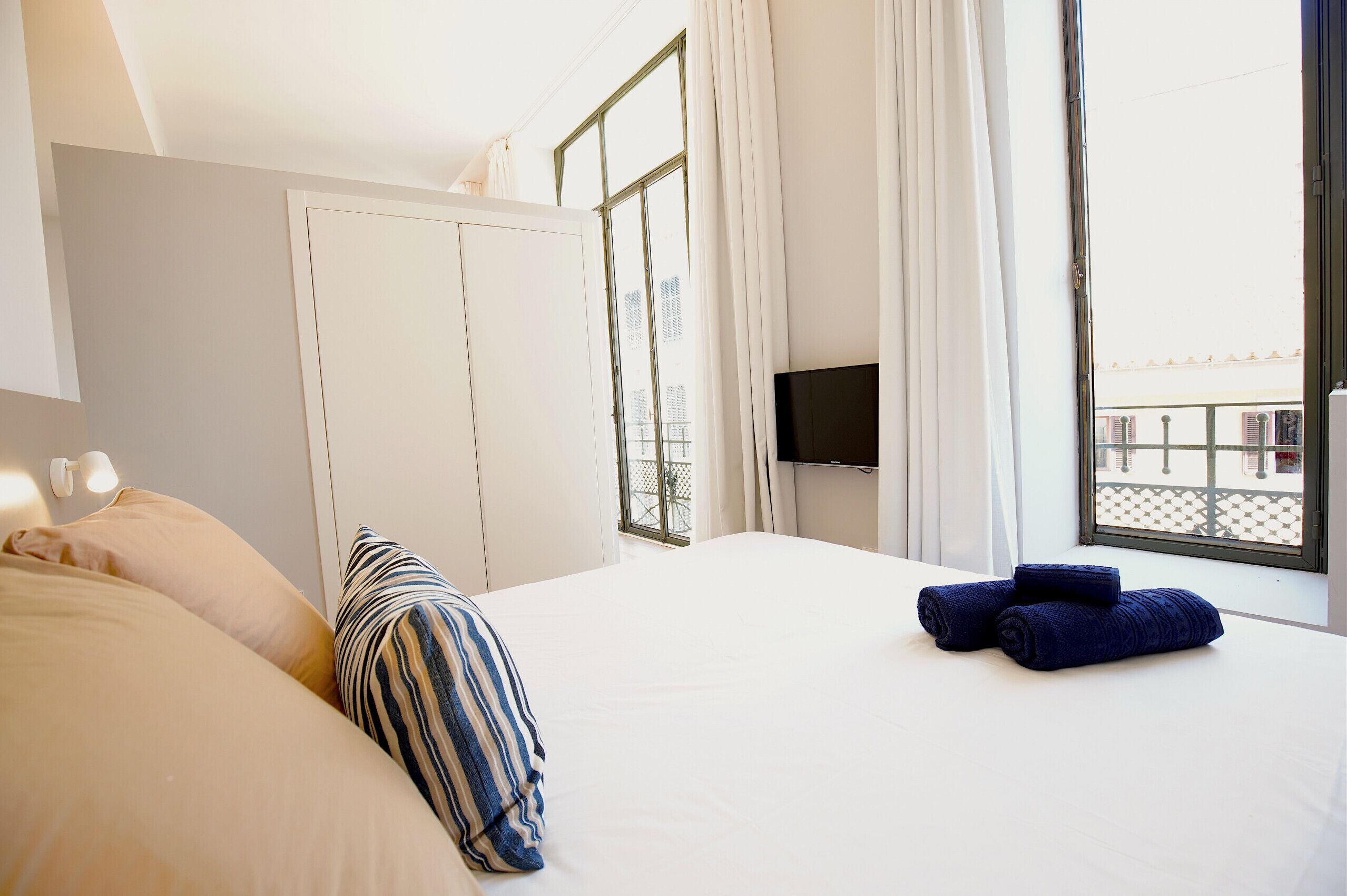 Habitación de hotel con cama, almohadas, televisor y ventana con cortinas.