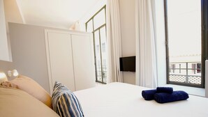 Habitación de hotel con cama, almohadas, televisor y ventana con cortinas.