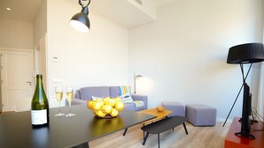 Una sala de estar moderna con una mesa de comedor, un sofá, un banco y un mueble para la televisión.