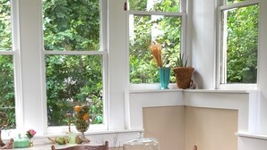 A dining area with a wooden table and chairs, a decorative centerpiece, and a view of greenery through large windows. - Lovely Historic Home Downtown Columbus  (Columbus)
