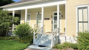 A two-story house with a covered porch, a front door, and a staircase leading to the entrance. - Lovely Historic Home Downtown Columbus  (Columbus)
