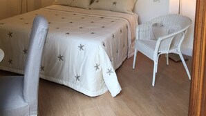 Une chambre à coucher avec un lit, deux lampes de chevet, une chaise et un tableau au mur.