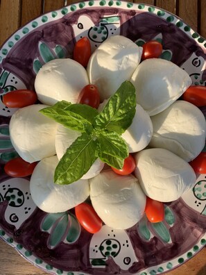 Een bord met mozzarella balletjes, kerstomaatjes en basilicumblaadjes.