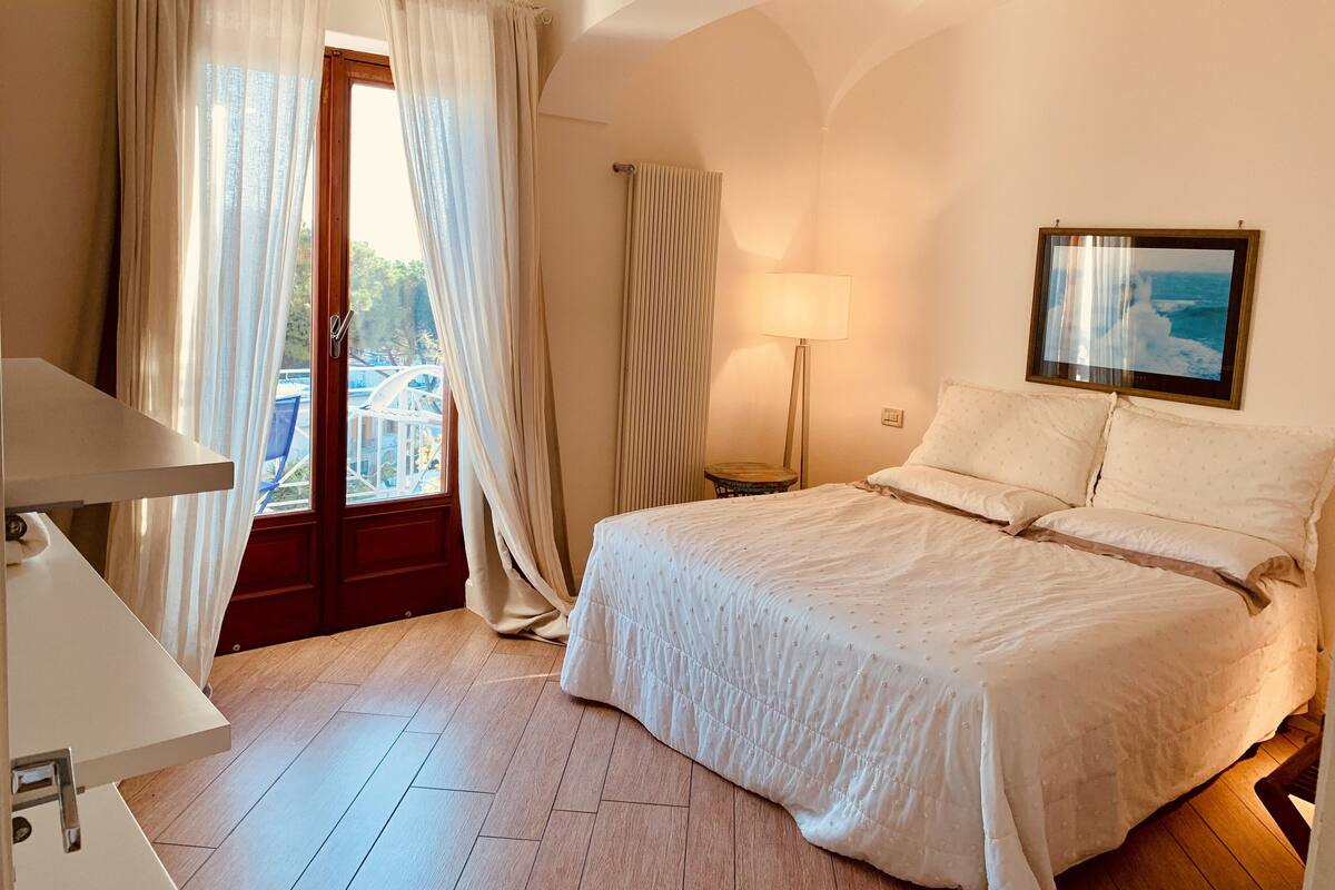 Ein Hotelzimmer mit Bett, Schreibtisch, Lampe und einem Fenster mit Vorhängen.