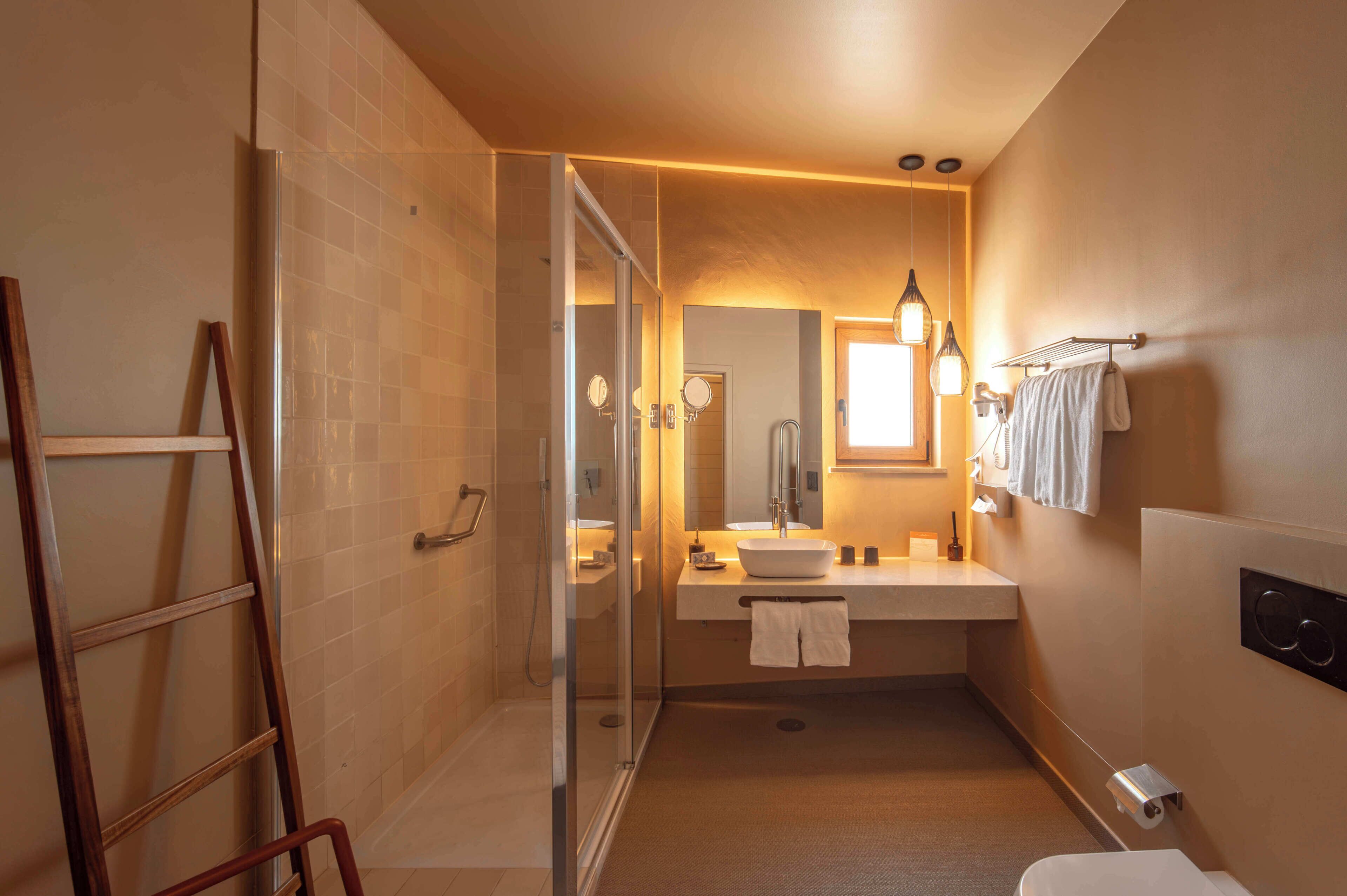 A bathroom with a glass shower enclosure, a sink with a mirror, and a towel rack.