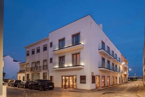 A multi-story hotel with a white facade, balconies, and a parking area with several cars. - Authentic Tavira Hotel (Tavira)