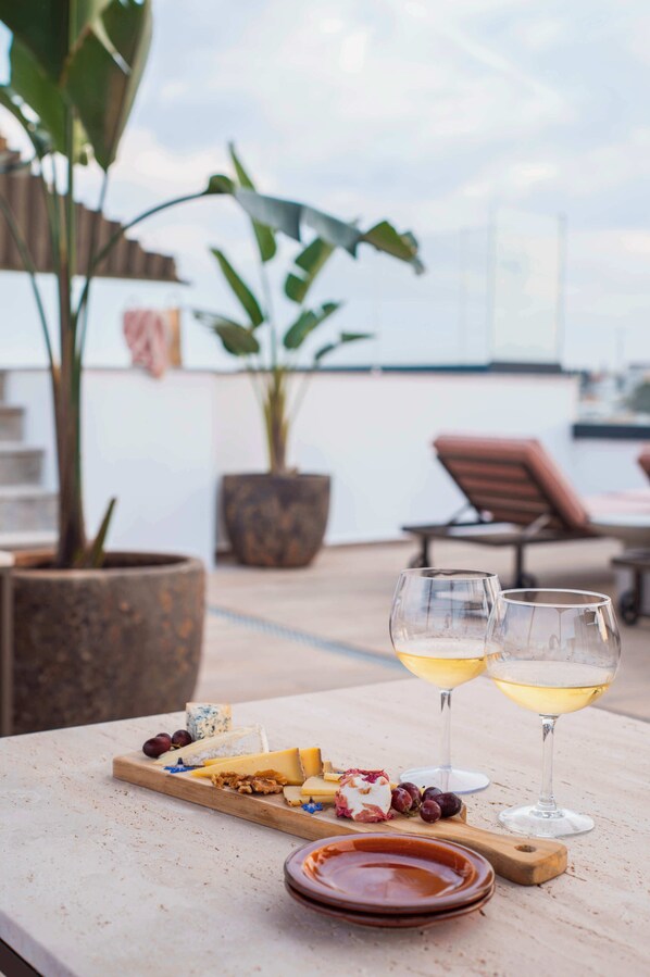 A table with a cheese board, two glasses of wine, and a potted plant. - Authentic Tavira Hotel (Tavira)