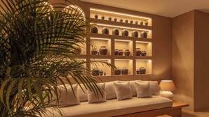 Ein modernes Interieur mit einer Couch, Regalen mit Vasen, einer Lampe und einer großen Pflanze.