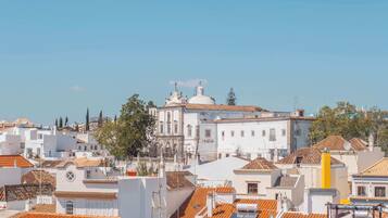 A white building with a dome and bell tower, surrounded by other buildings with orange-tiled roofs.
