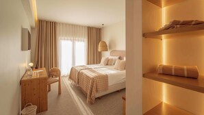 Ein Hotelzimmer mit Bett, Nachttisch, Stuhl und einem Regal mit Handtüchern.