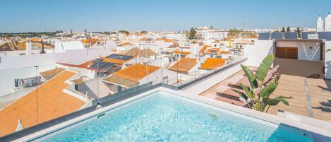 A rooftop pool with a view of a residential area and a clear sky.