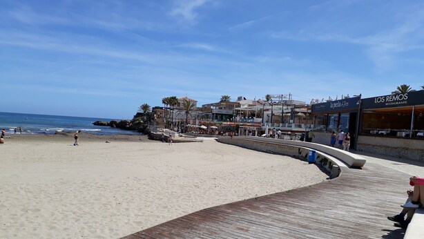 A beach with a wooden boardwalk, shops, and a restaurant named 'Los Remos'. - Love 2 bed apartment.  Sleeps 4 with wifi, satellite TV and pool. (Xàbia)