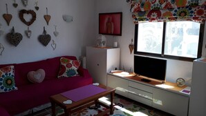 A cozy living room with a red sofa, a wooden coffee table, and a TV on a white cabinet. - Love 2 bed apartment.  Sleeps 4 with wifi, satellite TV and pool. (Xàbia)