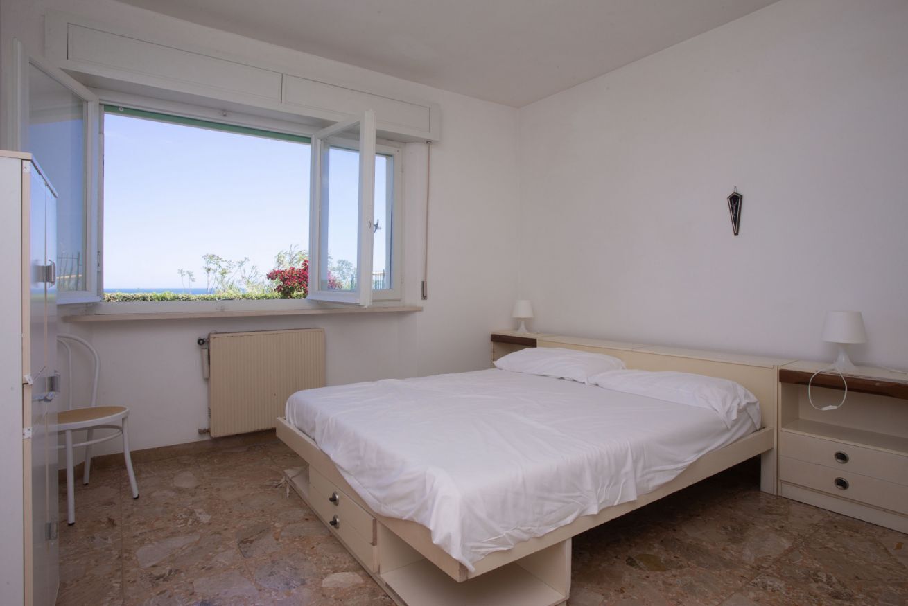 A bedroom with a bed, a chair, a window, and a radiator.