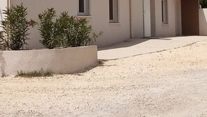 Ein Gebäude mit einem Ziegeldach, einer Schotterauffahrt und einem großen Baum im Hintergrund.