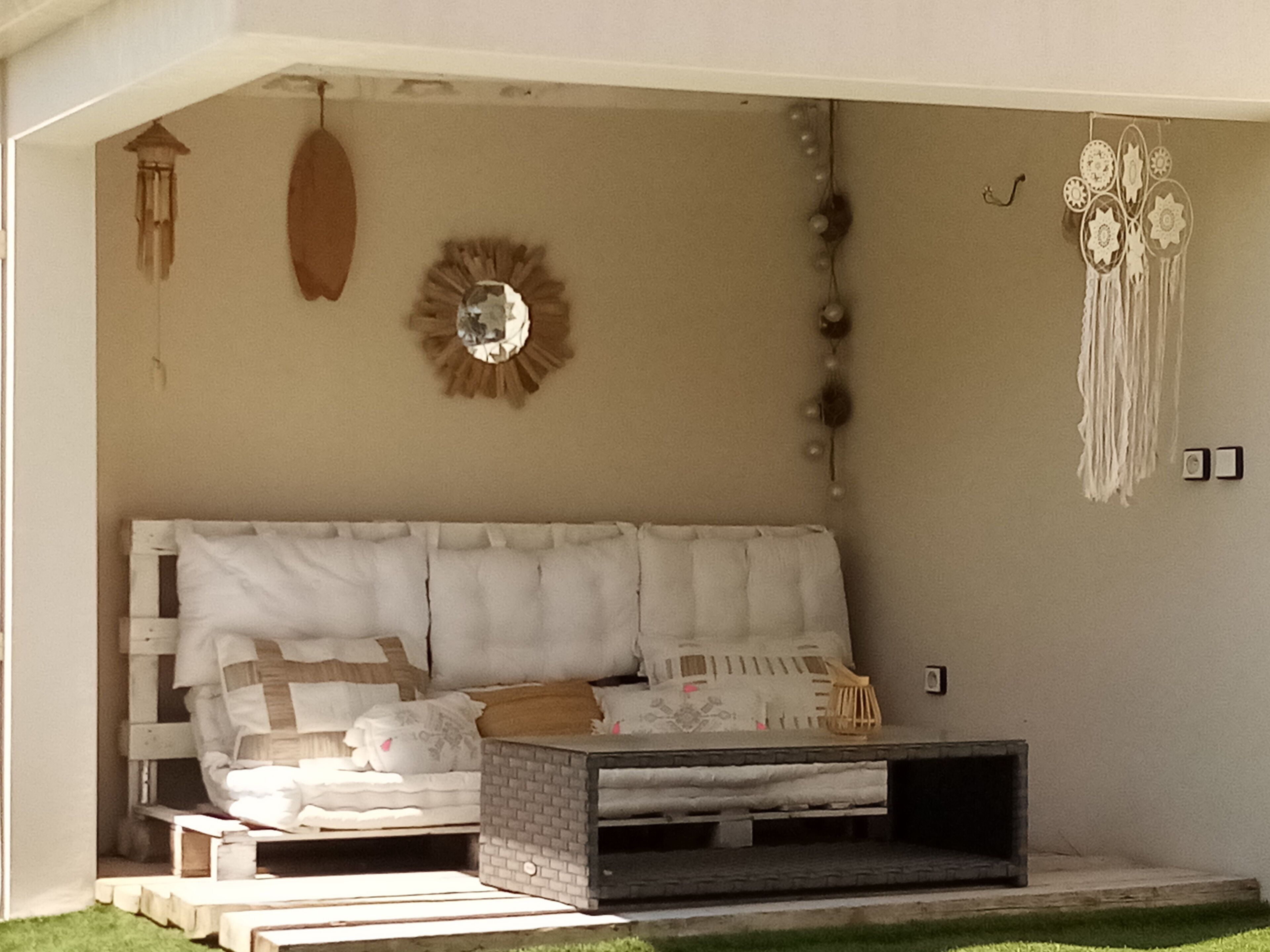 A cozy room with a bed, a small table, and a wall decorated with a mirror, dreamcatcher, and wall hanging.