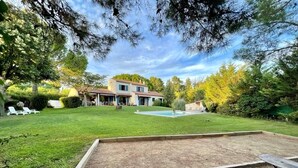 Un jardin avec une piscine, une terrasse en bois et un banc.