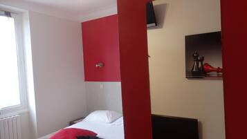 A bedroom with a bed, a red wall, a white wall, and a black headboard.