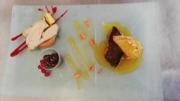 Plat rectangular amb diversos aliments, com un tros de carn, fruita i un bol petit de baies.
