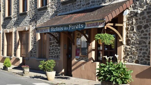 Un edificio de piedra con un cartel que indica 'Relais des Forêts' y 'Bar Tabac Hotel'.
