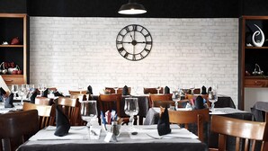 Un restaurante con mesas dispuestas para comer, un reloj en la pared y una lámpara colgante arriba.
