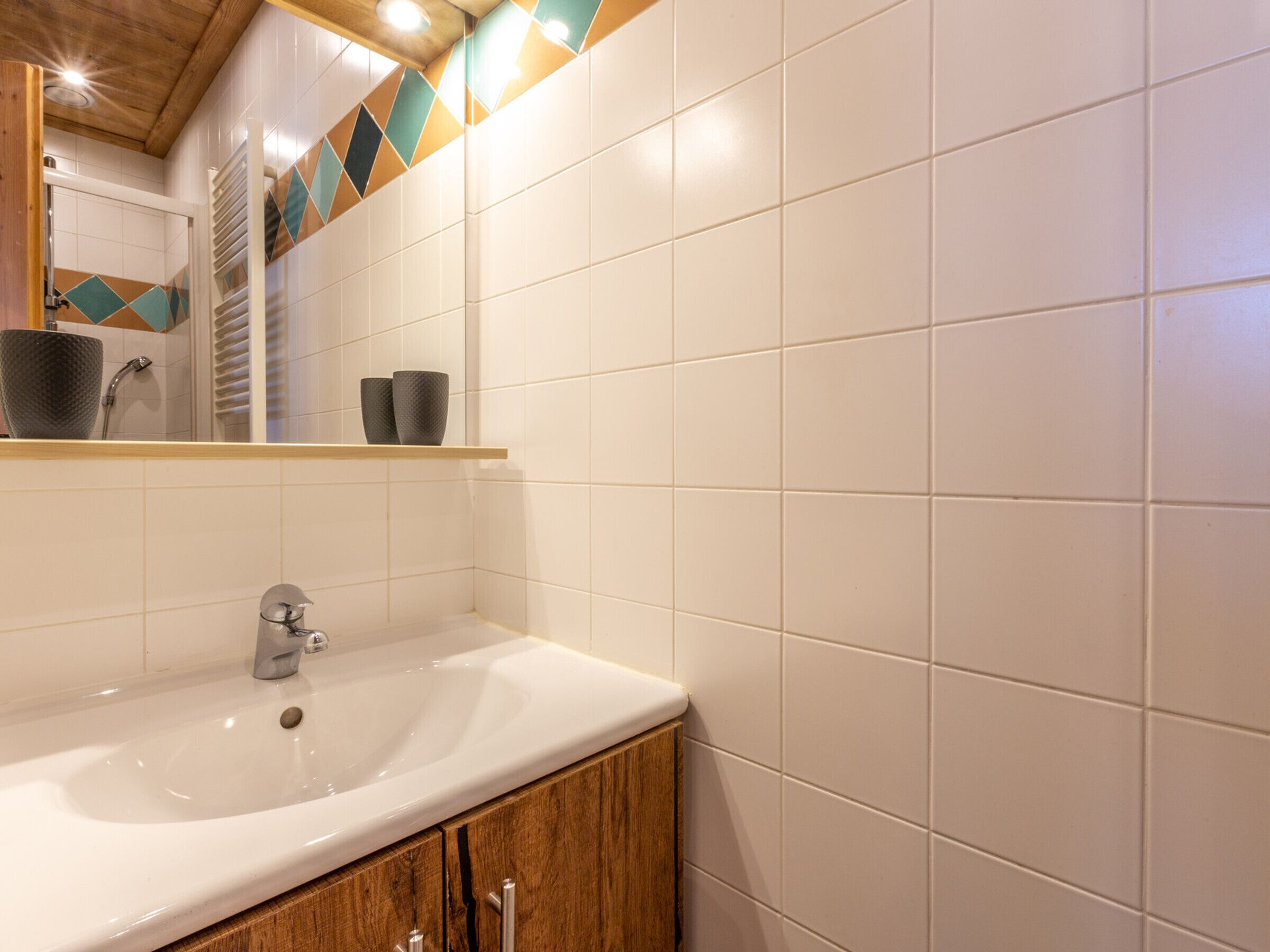 A bathroom with a white sink, wooden cabinet, and a mirror.