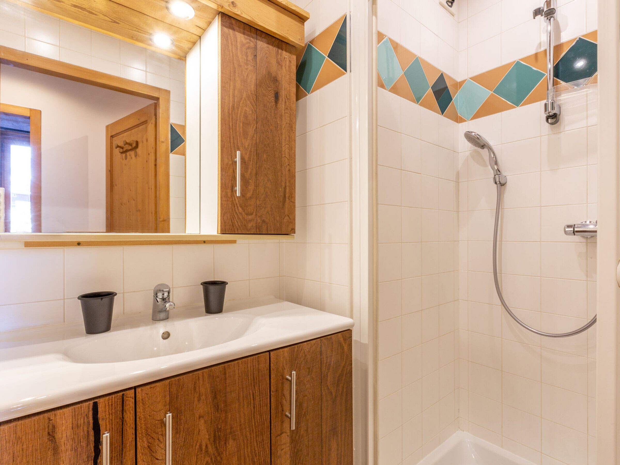 A bathroom with a wooden vanity, a sink, and a shower with a handheld showerhead.